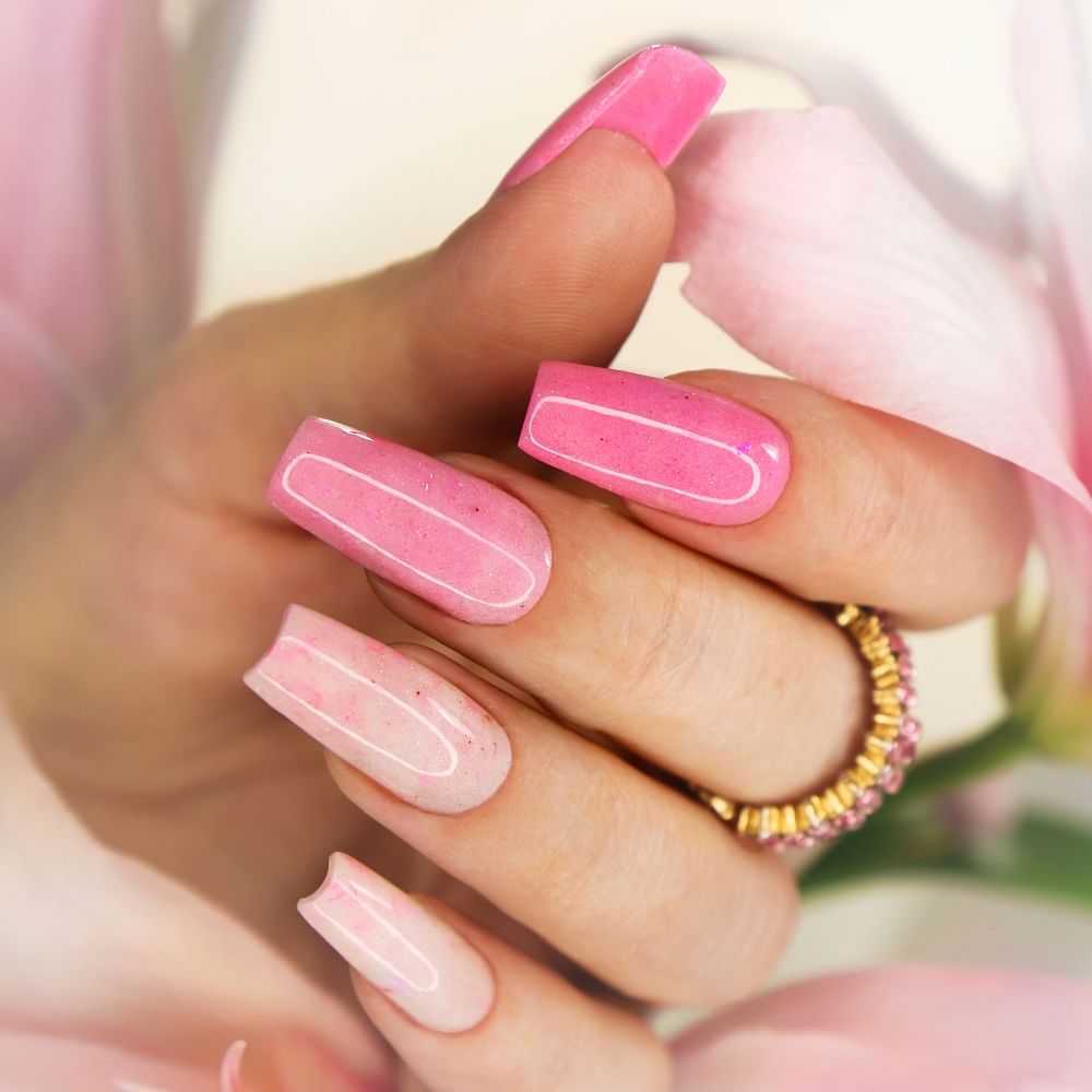 Close-up of pink ombre nail art with glitter details.